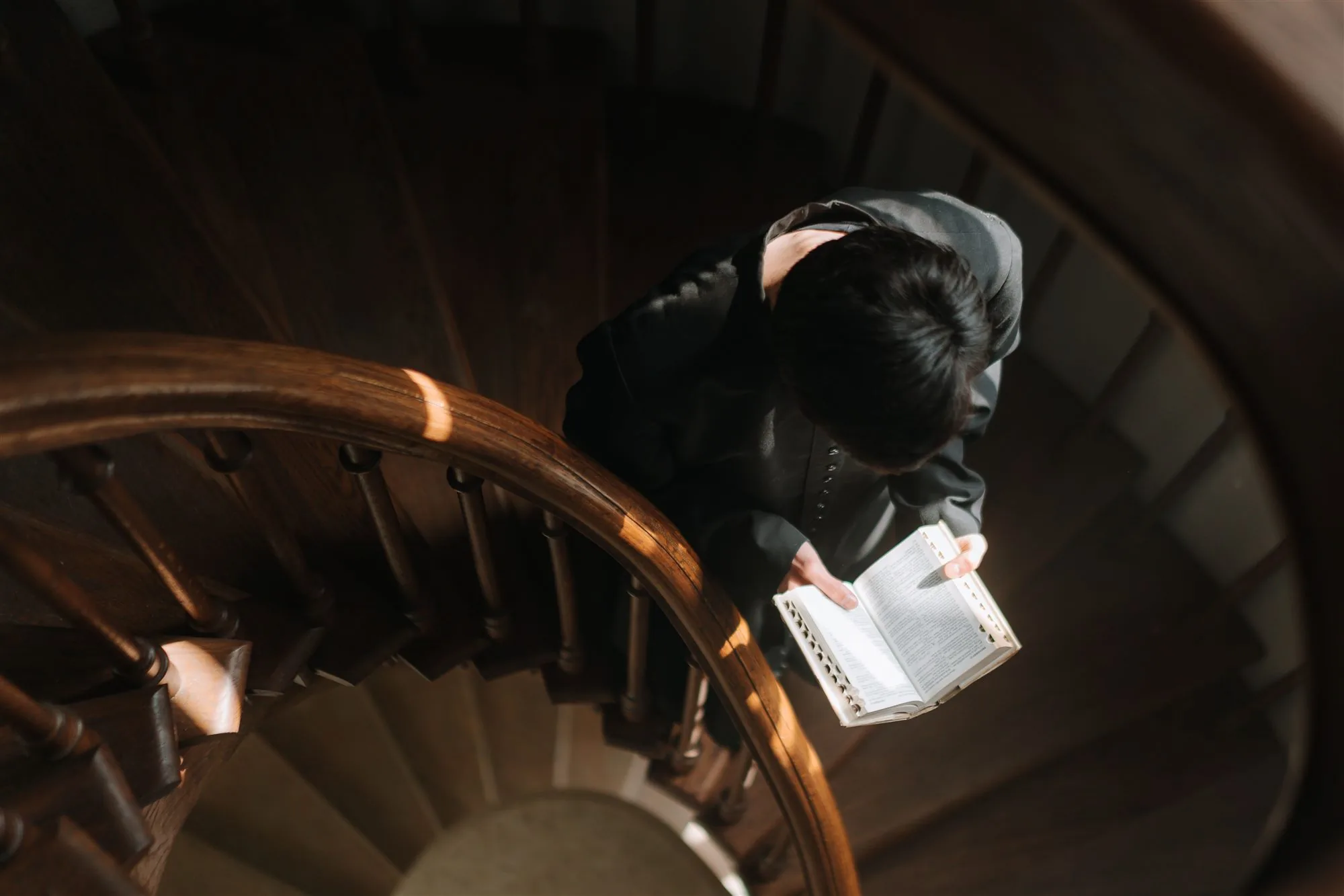 A seminarian reading while ascending a wooden staircase