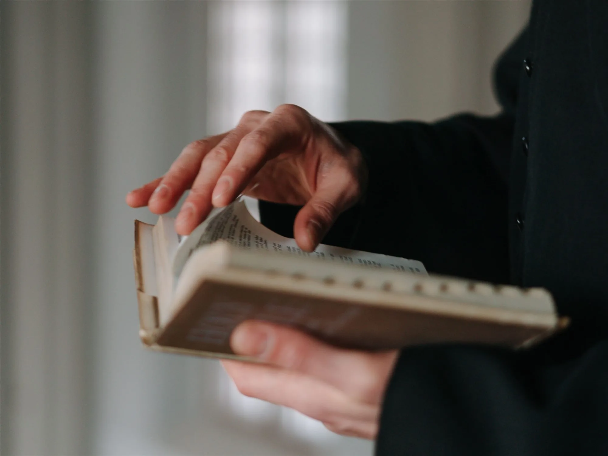A cleric turning the pages of a theological book