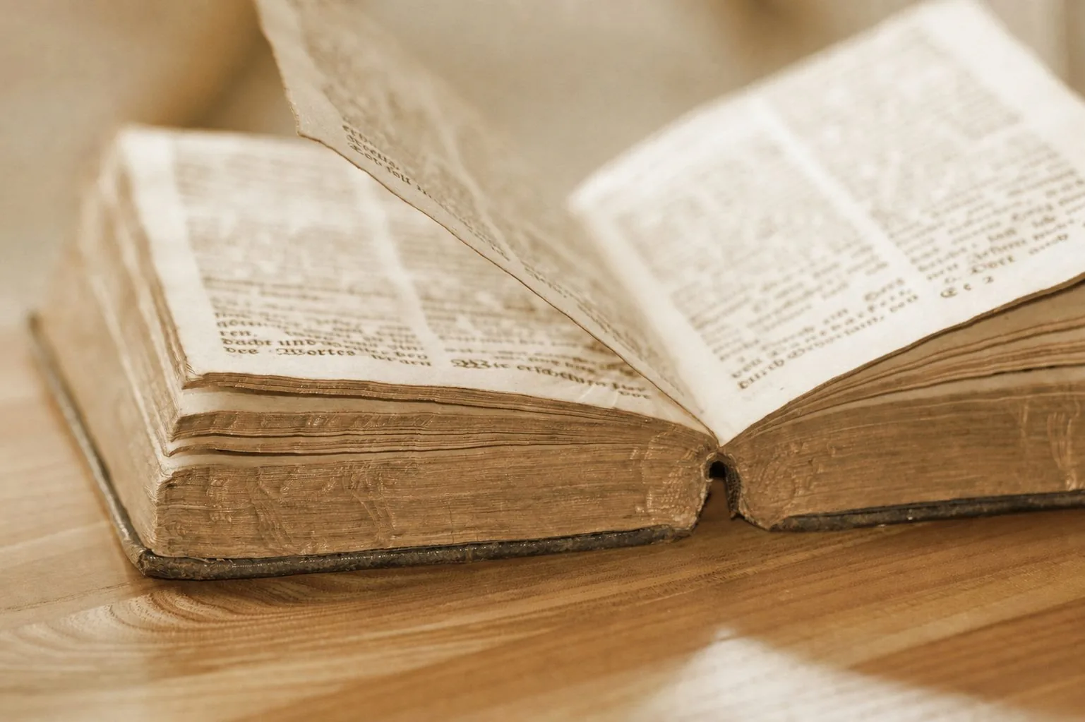 An open historic book with a turning page