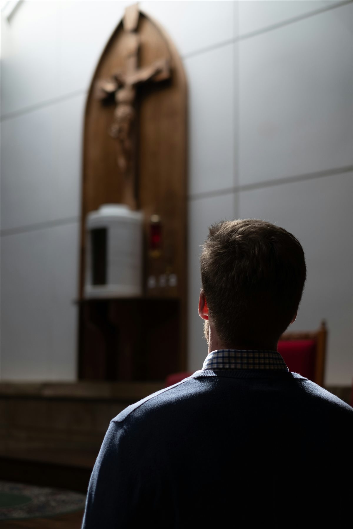 A man seated in prayer before a crucifix in a church