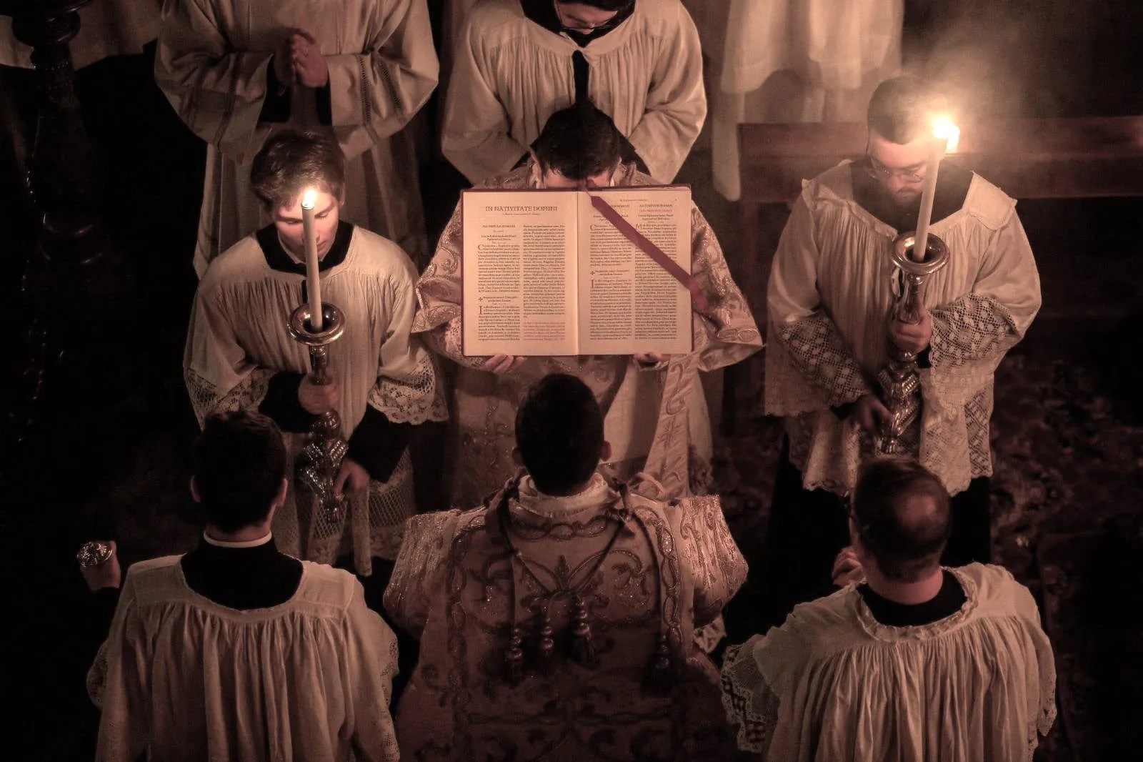 Clergy gathered around an illuminated liturgical book during worship